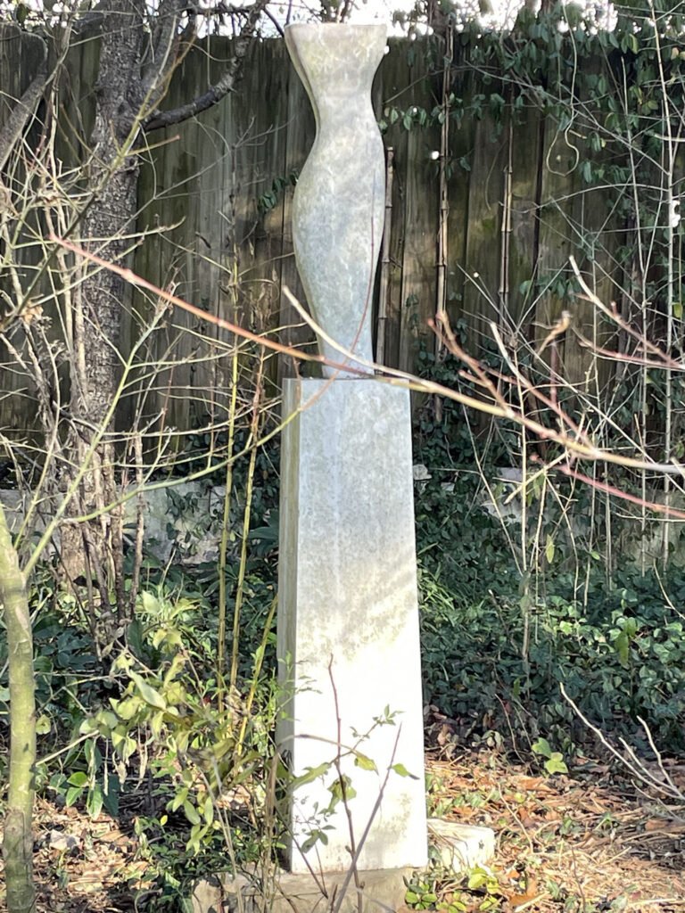 Mini Torso by Bruce Bennett, a slender Tennessee limestone torso sculpture displayed outdoors on a stone pedestal