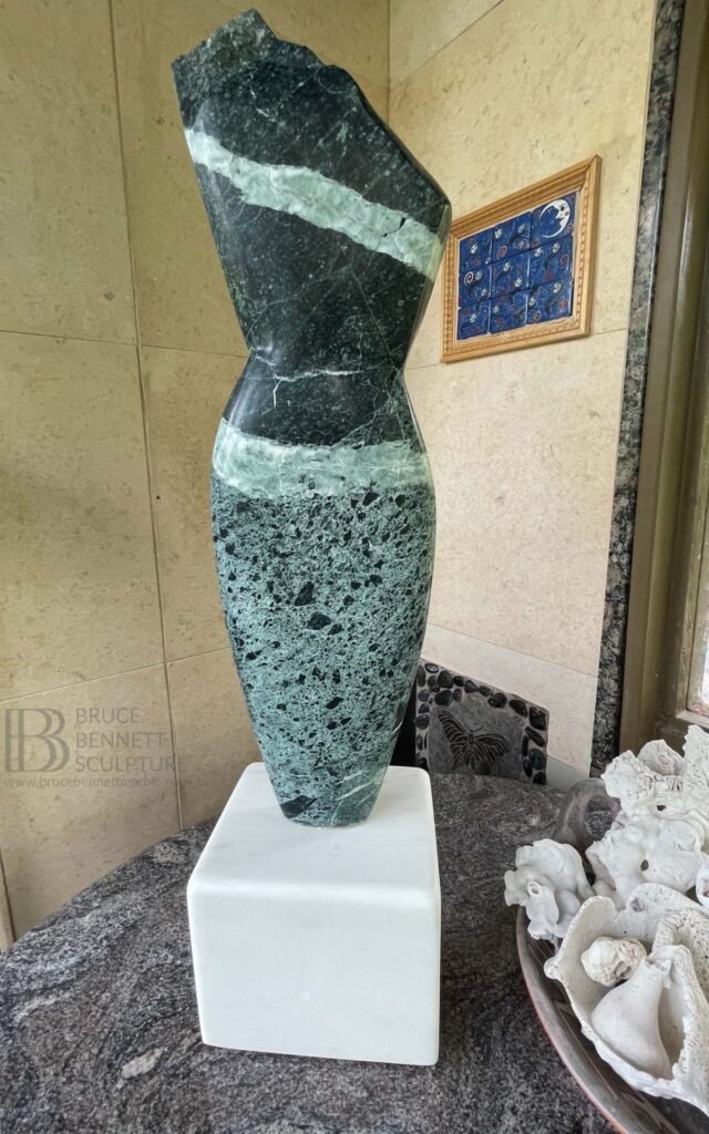 Abstract torso sculpture by Bruce Bennett carved from dark green Verde Alpi marble with a broad white vein