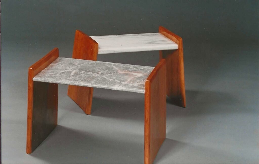 Two early benches by sculptor Bruce Bennett combining marble seats with warm-toned wooden supports.