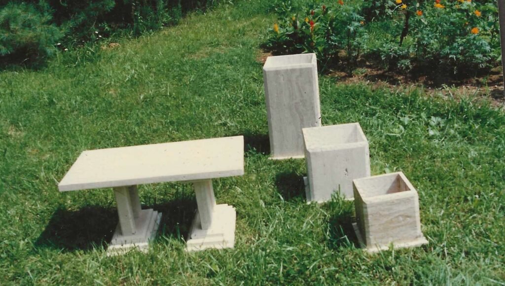 Limestone bench by sculptor Bruce Bennett displayed with three coordinating limestone planters.