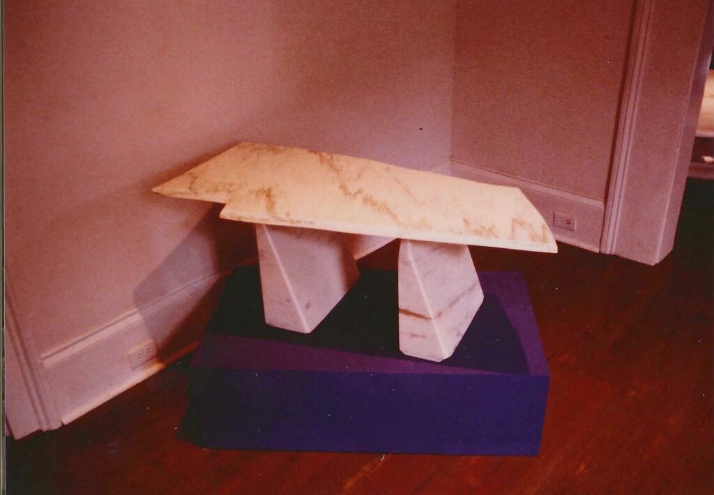 Bruce Bennett geometric marble coffee table with an irregular notched top and paired faceted pedestal bases.