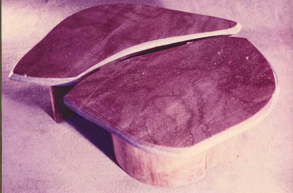 Pair of Bruce Bennett low tables with organically shaped stone tops and curved wood bases.