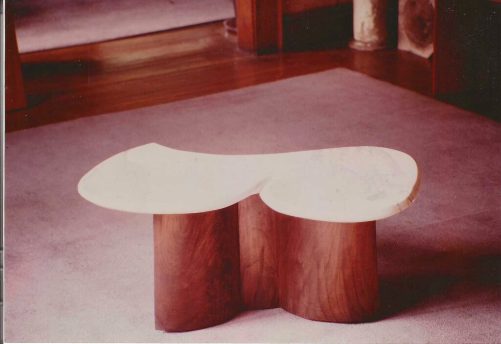 Bruce Bennett low table featuring a biomorphic stone top supported by paired curved wood forms.
