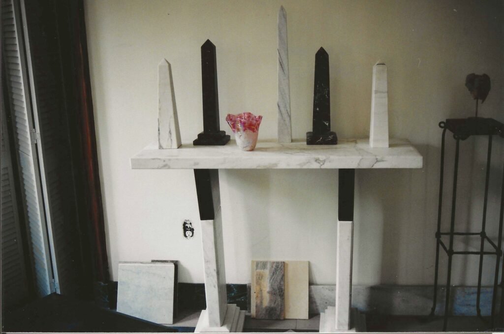 Bruce Bennett highboy table with duo-marble legs, displaying a group of his marble obelisk sculptures.