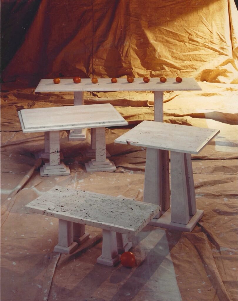 Group of Bruce Bennett tables in Italian Cream marble, featuring varied geometric forms and architectural stone bases.