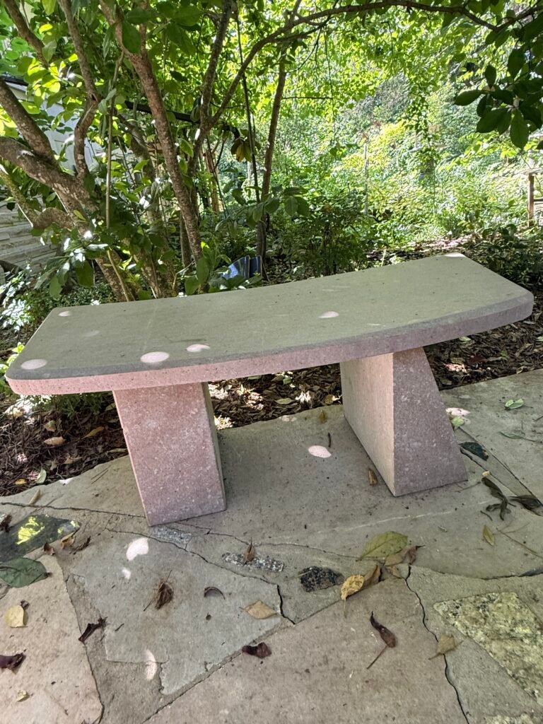 Pink Tennessee marble bench by sculptor Bruce Bennett with a gently curved stone seat and angled slab supports.