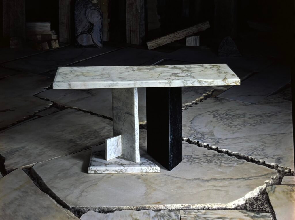 Bruce Bennett table with a veined white marble top, asymmetrical stone supports, and contrasting black marble accent.