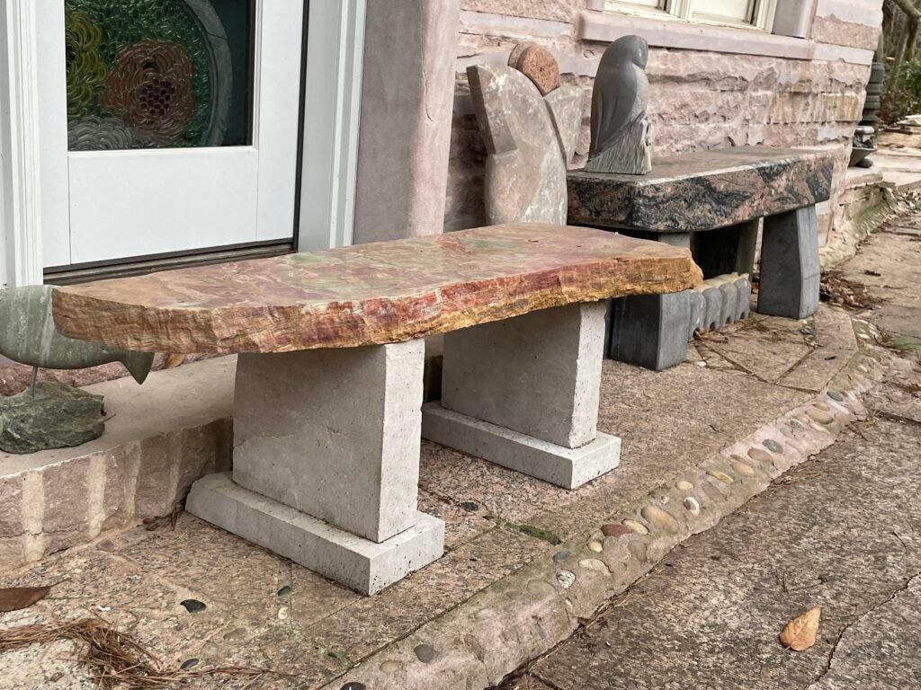 Bench by sculptor Bruce Bennett with a pink onyx slab seat and geometric limestone supports.