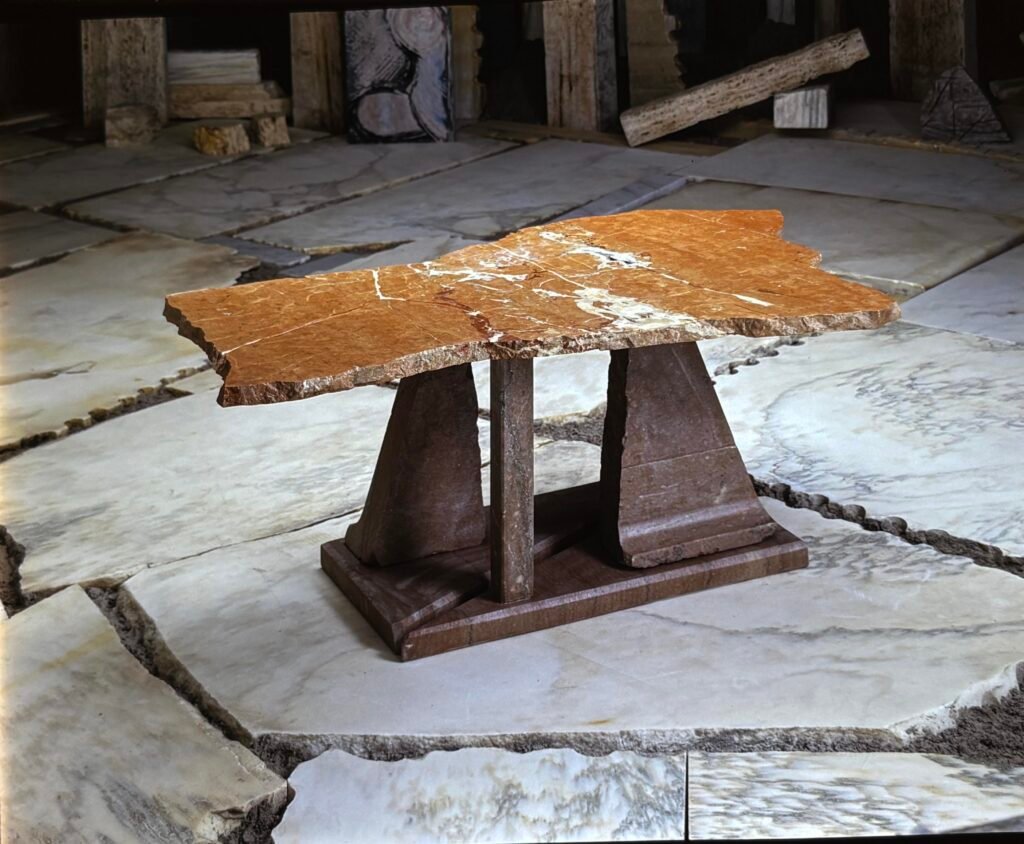 Bruce Bennett sculptural table with a natural-edge Rosso marble top and contrasting stone base.