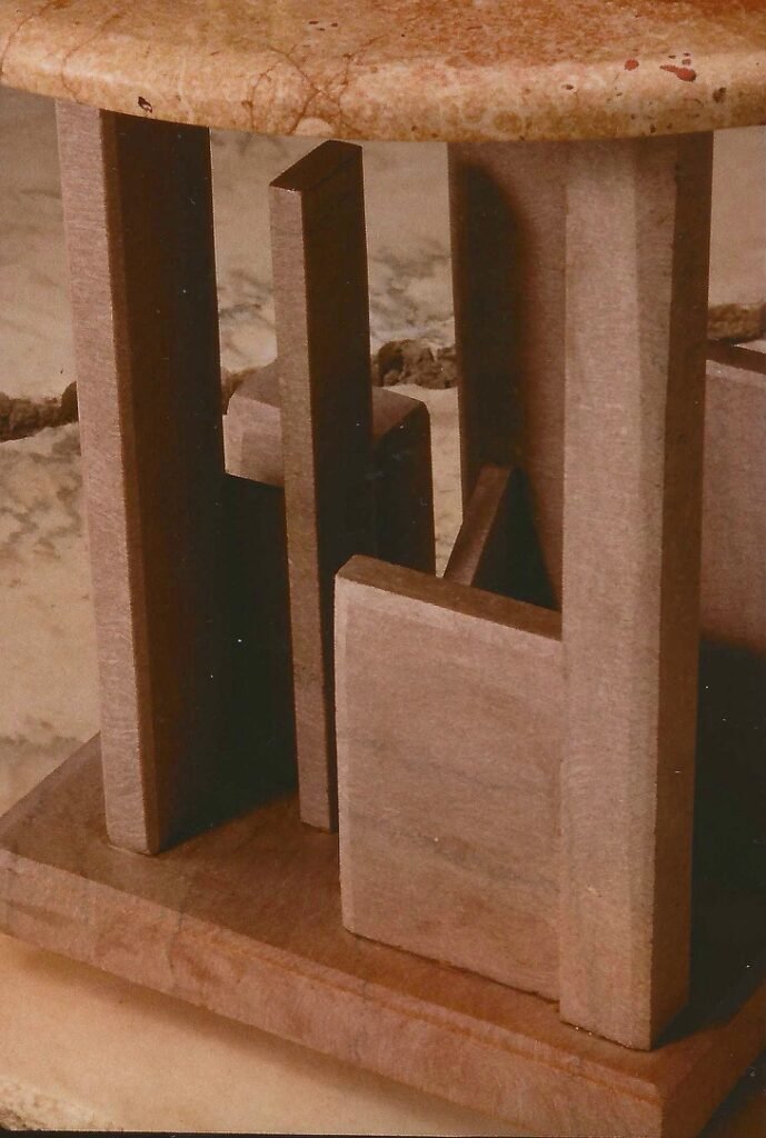 Artist detail showing the sculptural limestone base of Bruce Bennett’s table with an asymmetrical Rosso marble top.